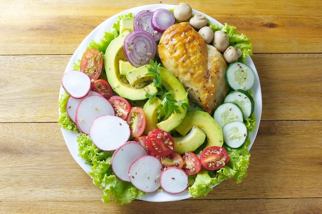 Healthy eating plate of grilled chicken breast and avocado and vegetable salad over rustic wooden table Ketogenic and Paleolithic Diet