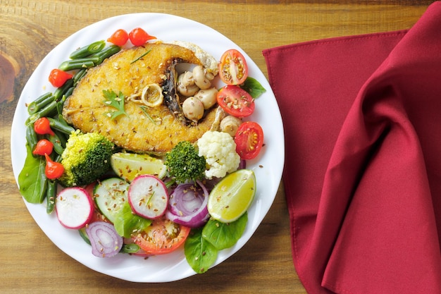 Healthy eating plate of grilled fish and vegetable salad over rustic wooden table Ketogenic and Paleolithic Diet