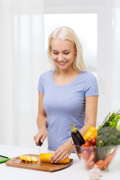 healthy eating, vegetarian food, cooking , dieting and people concept - smiling young woman chopping vegetables at home