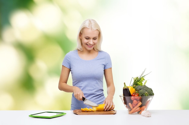 healthy eating, vegetarian food, dieting and people concept - smiling young woman cooking vegetables with tablet pc computer over green natural background