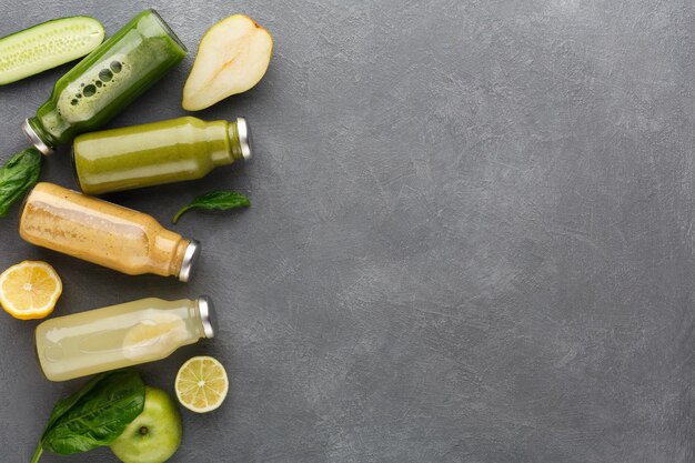 Healthy food. Assortment of fruit and vegetables detox smoothies in glass bottles with ingredients on gray background, copy space, top view