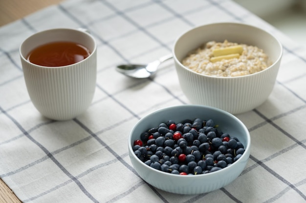 Healthy food breakfast with oatmeal porridge in bowl with summer berries slice of butter mug tea