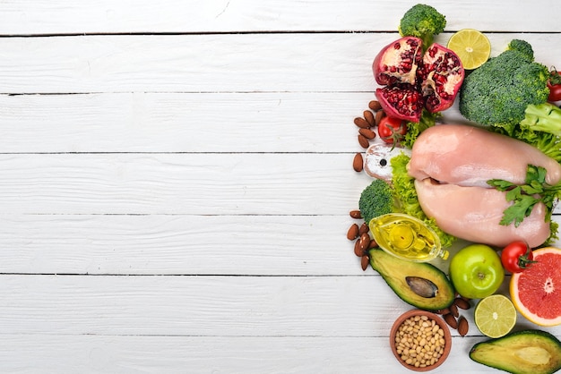 Healthy food Chicken fillet avocado broccoli fresh vegetables nuts and fruits On a wooden background Top view Copy space