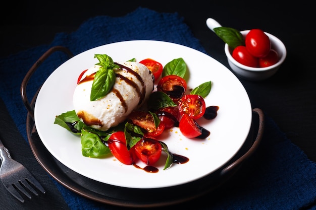 Healthy food concept rustic Caprese Salad on black background with copy space