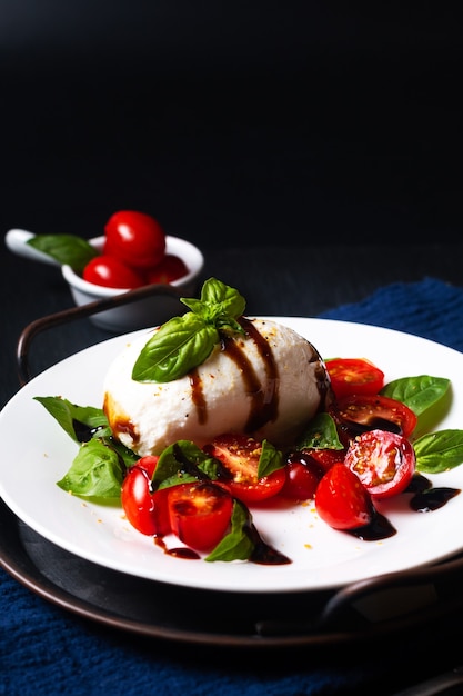 Healthy food concept rustic Caprese Salad on black background with copy space