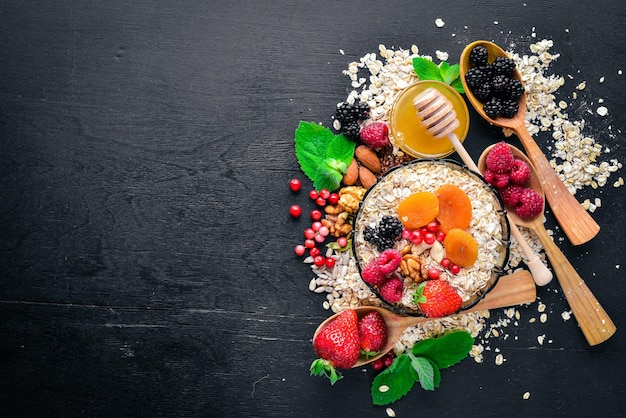 Healthy food Fresh wild berries copper nuts oatmeal dried fruits and seeds On a wooden background Top view Free space for text