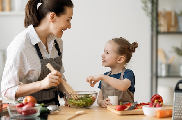 Healthy food at home. Happy family in the kitchen. Mother and child daughter are preparing proper meal.