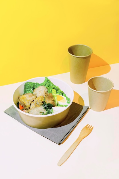 Healthy food lunch in kraft paper carton eco box disposable bowl container cups on yellow background chicken eggs greens dinner Take away delivery environment protection vertical top view