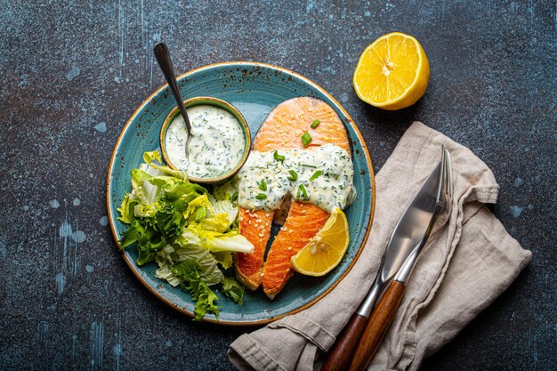 Healthy food meal cooked grilled salmon steaks with dill sauce and salad leafs on plate