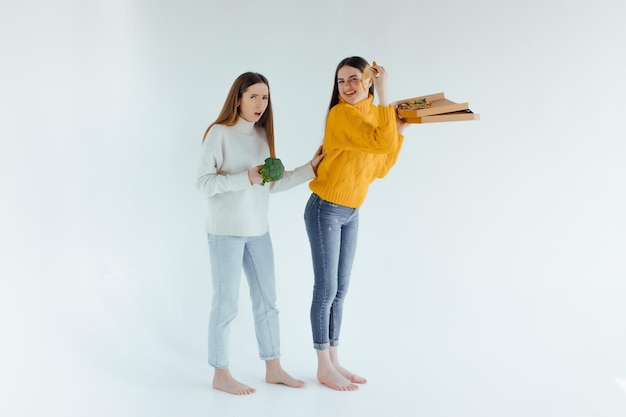 Photo healthy food. one woman is holding a pizza and the other a broccoli