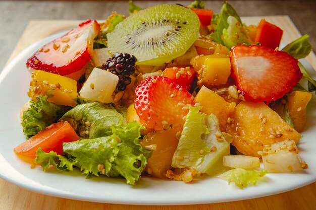 Healthy fresh fruit salad with fried chicken on a wooden background contains kiwi strawberry and tropical fruits