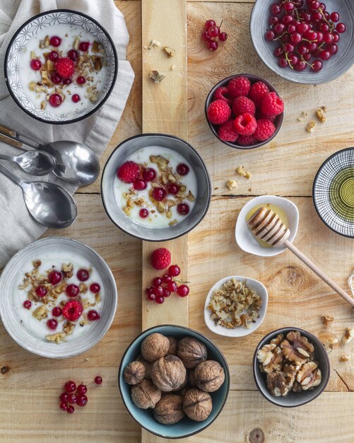 Healthy fresh Greek yogurt dessert or breakfast topped with walnuts and honey and served in individual bowls on a rustic wooden board