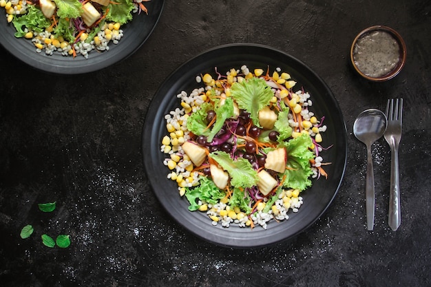 Healthy fruit and vegetable salad, lettuce, corn, grapes, apples on plate.