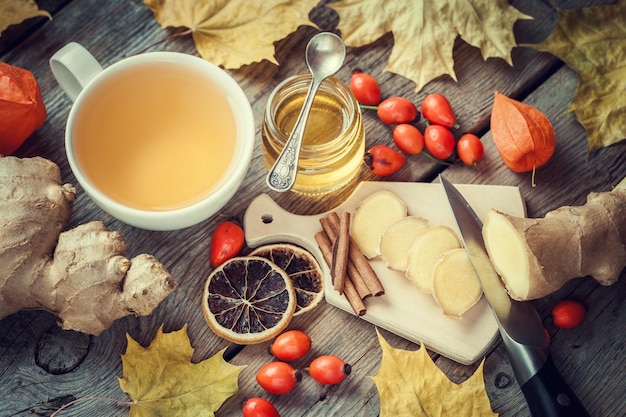 Healthy ginger tea jar of honey ginger roots dried lemon slice wild briar and cinnamon on table