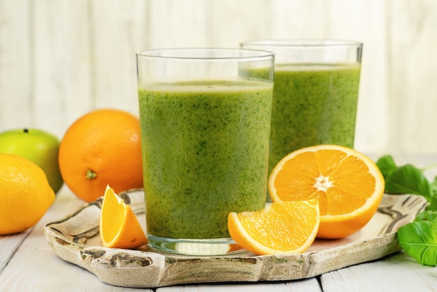 Healthy green smoothie with spinach, mango, orange,lime, apple,citrone in glass jars.