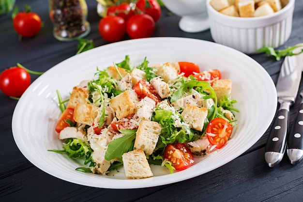 Healthy grilled chicken Caesar salad with tomatoes, cheese and croutons.