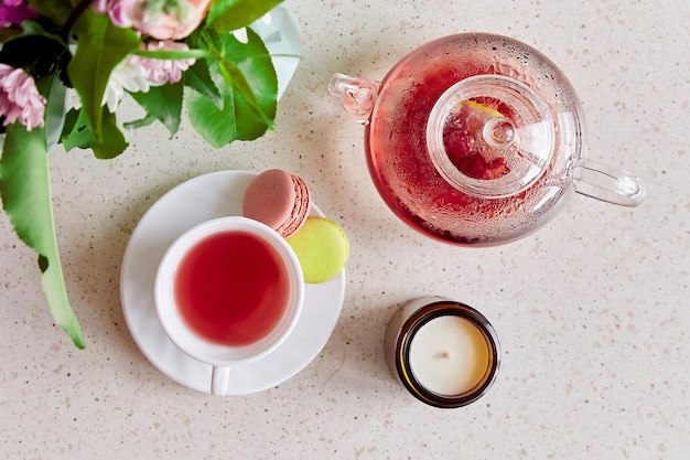 Healthy herbal natural tea glass teapot macaroons candle and bouquet of flowers Herbal tea top view Coziness self care relaxing wellness lifestyle