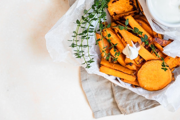 Healthy homemade baked sweet potato wedges with cream dip sauce and herbs Healthy snack