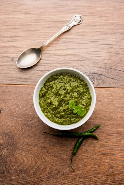 Photo healthy indian green chutney or sauce made using coriander, mint and spices. isolated over moody background. selective focus