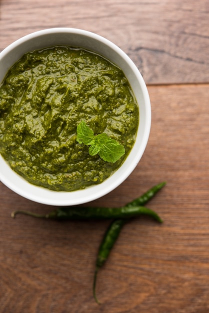 Photo healthy indian green chutney or sauce made using coriander, mint and spices. isolated over moody background. selective focus