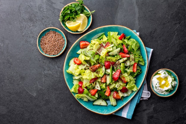 Healthy lettuce strawberry salad with linen seeds on blue plate top view