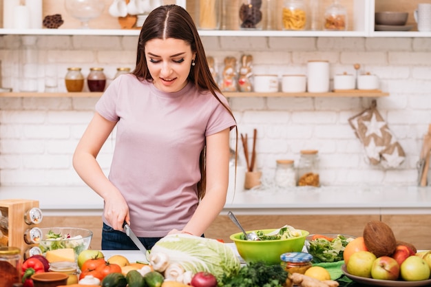 Healthy lifestyle. Organic dinner recipe. Food to be fit. Young woman at kitchen counter preparing meal.