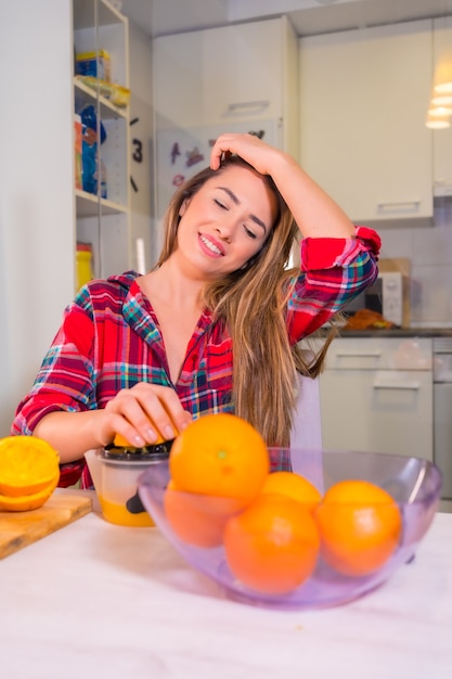 Healthy lifestyle, portrait of a blonde Caucasian woman squeezing oranges making a fresh orange juice