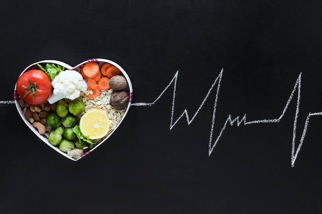 Healthy living concept with vegetables arranged in heartshape as an ecg life line on black background