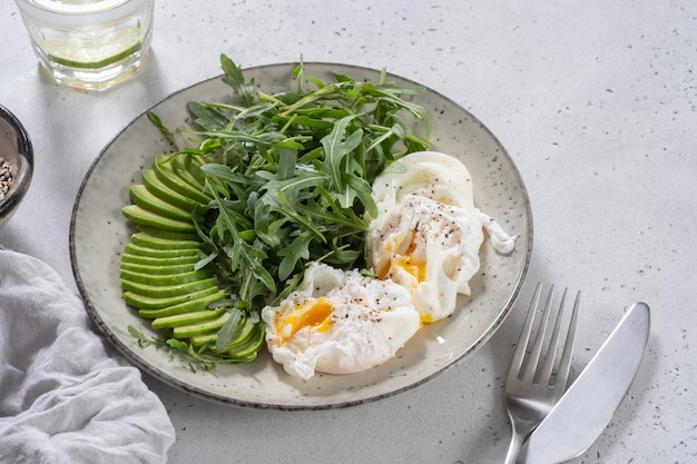 Healthy low carb breakfast poached eggs with avocado and arugula