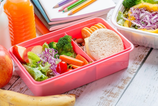 Healthy lunch box set of sandwich cheese with cracker and salad in box, banana and apple, orange juice and milk.