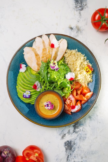 Healthy lunch plate with grilled chicken salad avocado couscous on blue plate