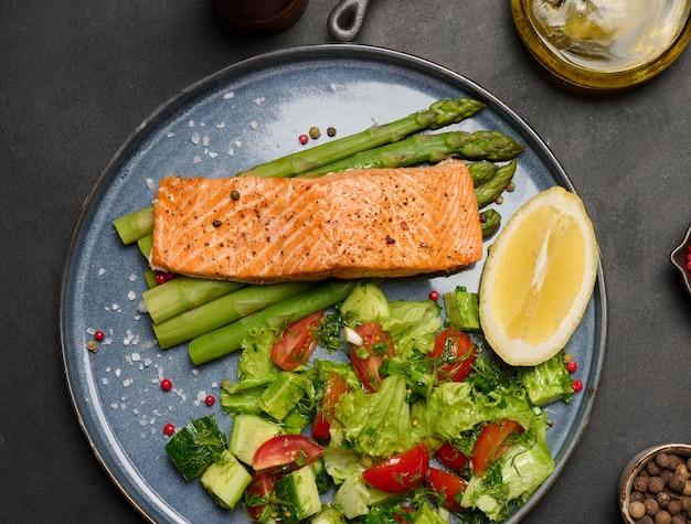 Healthy lunch with grilled salmon with asparagus and fresh tomato and cucumber