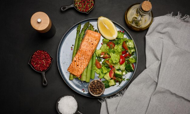 Healthy lunch with grilled trout with asparagus and fresh tomato and cucumber salad