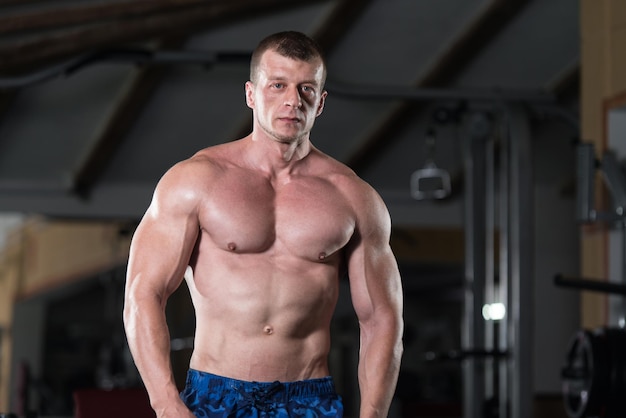 Healthy Man Standing Strong In The Gym And Flexing Muscles  Muscular Athletic Bodybuilder Fitness Model Posing After Exercises