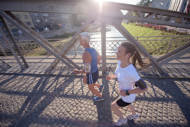 healthy mature couple jogging in the city  at early morning with sunrise in background