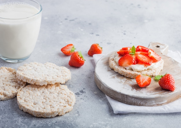 Healthy organic rice cakes with ricotta and fresh strawberries and glass of milk