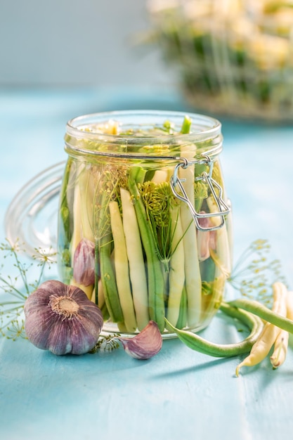 Healthy pickled yellow and green beans in jar with herbs