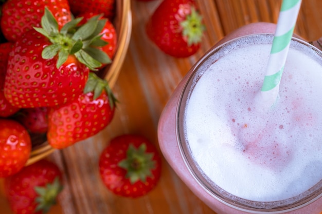 Healthy pink smoothie with strawberry in glass jars top view.