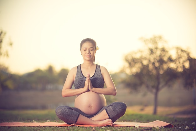 healthy pregnant woman doing yoga in nature outdoors