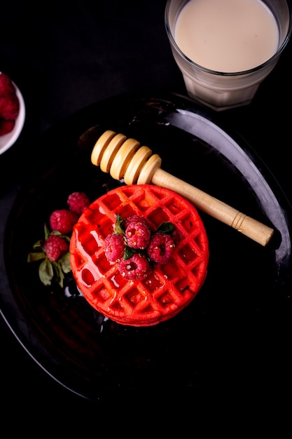 healthy red waffles with fruits and honey on black plate and black background in different angles