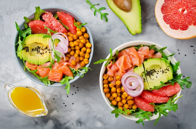 Healthy salad bowl with salmon, grapefruit, spicy chickpeas, avocado, red onion and arugula