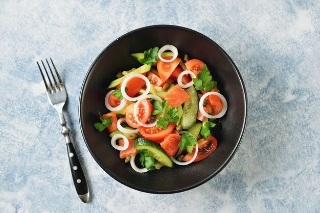 Healthy salad of cherry tomatoes, cucumber, celery, onions, capers and parsley with salted salmon.