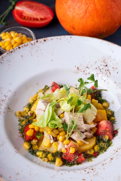 Healthy salad with chicken fillet corn tomatoes and baked pumpkin Closeup