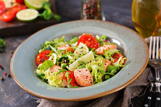 Healthy salad with fish. Baked salmon, tomatoes, lime and lettuce. 