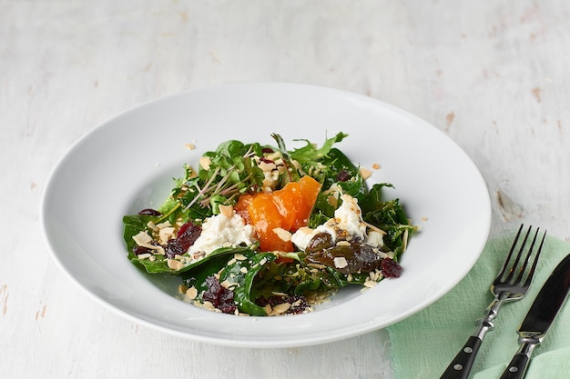 healthy salad with homemade stracciatella with persimmon and dried cranberries and almond flakes. 