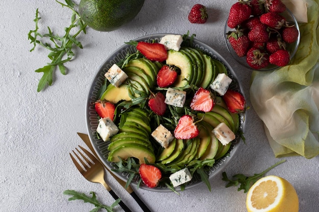 Healthy salad with strawberries avocado arugula and cheese dor blue dressed with balsamic in a plate