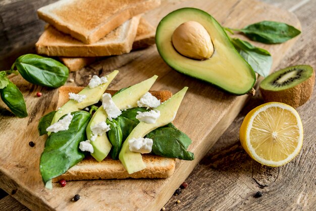 Photo healthy sandwich with cheese and avocado on wood board on foliage background