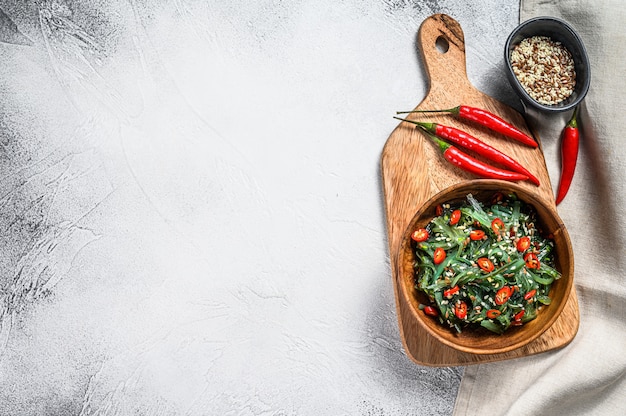 Healthy seaweed chuka salad with greens and red chili pepper. Gray background. Top view. Copy space