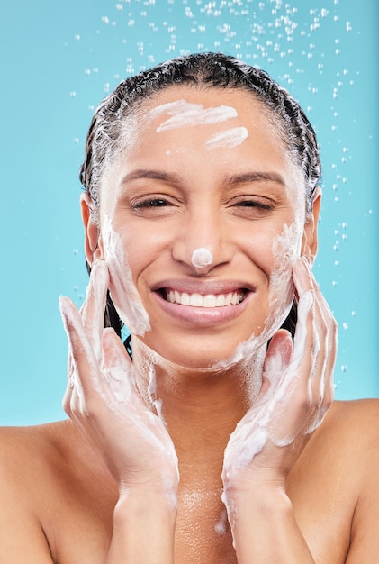 Healthy skin is happy skin. Shot of a young woman washing her face against a blue background.