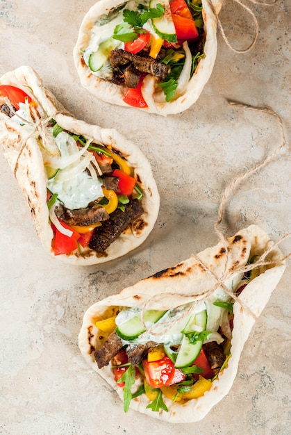 Photo healthy snack, lunch. traditional greek wrapped sandwich gyros - tortillas, bread pita with a filling of vegetables, beef meat and sauce tzatziki